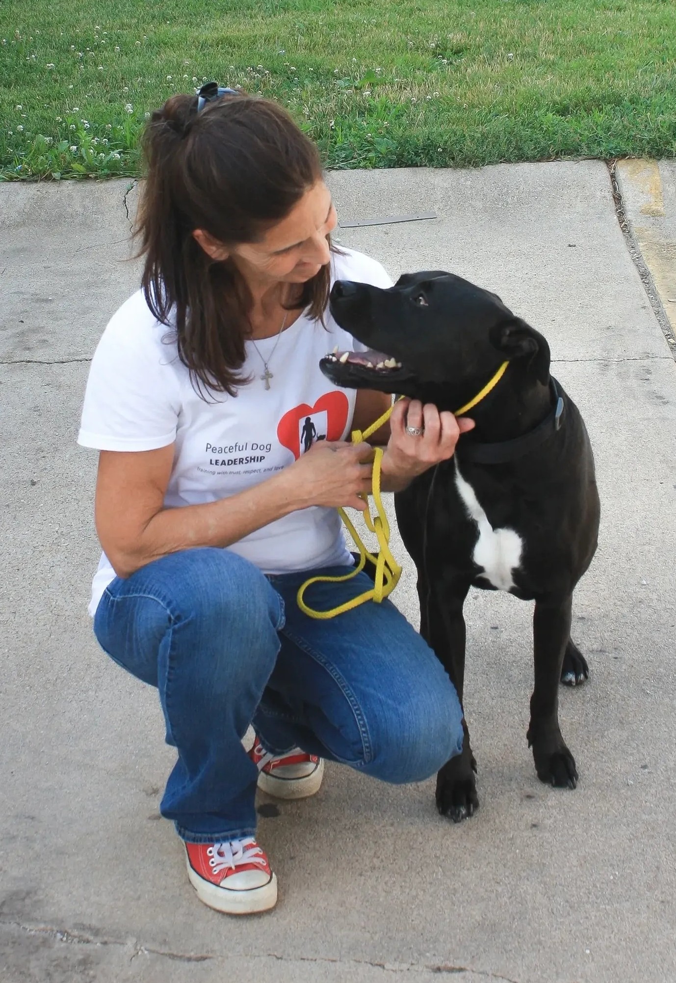 Jackie kneeling with a black dog.